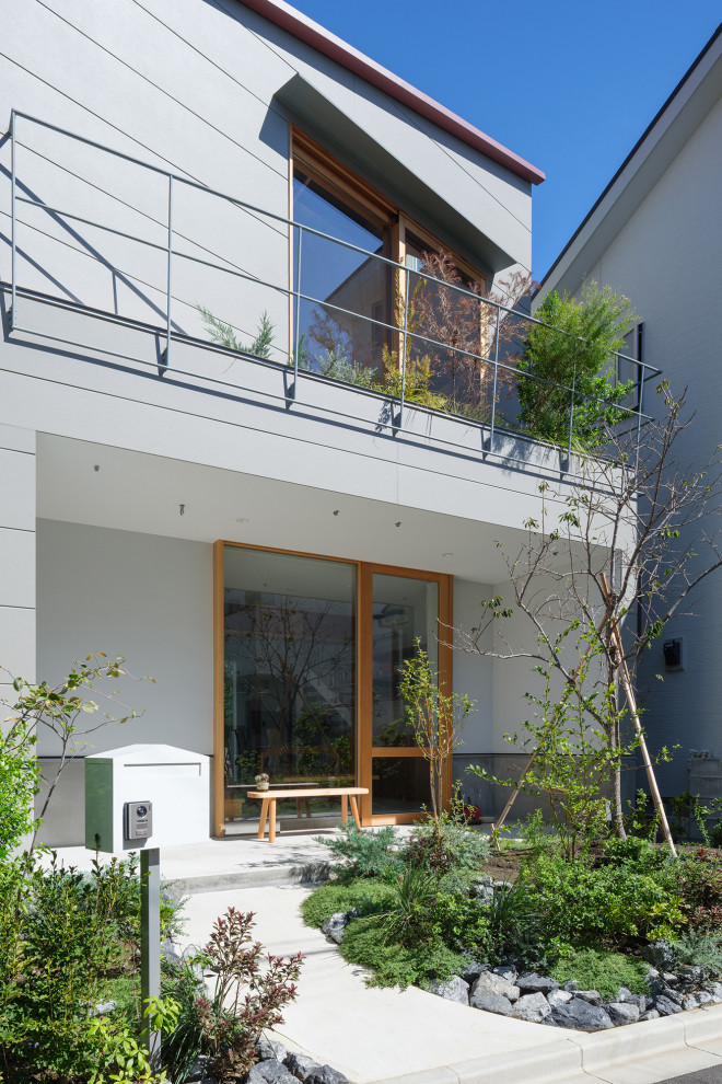Cette photo montre une façade de maison grise moderne de taille moyenne et à deux étages et plus avec un revêtement mixte, un toit à deux pans, un toit en métal et un toit rouge.
