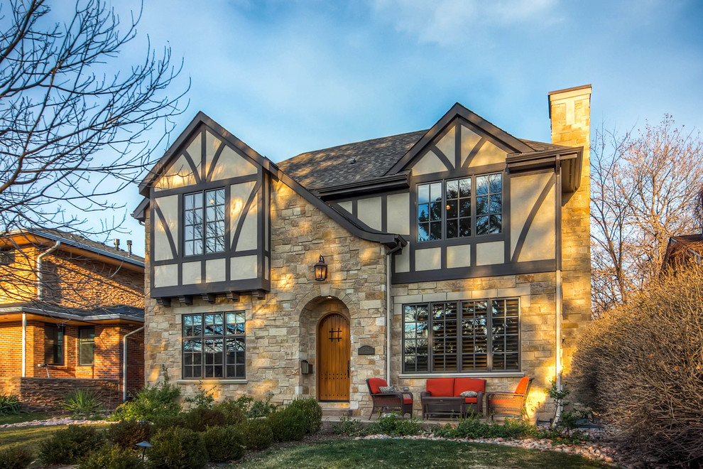 This is an example of a large transitional two-storey beige exterior in Denver with stone veneer and a gable roof.
