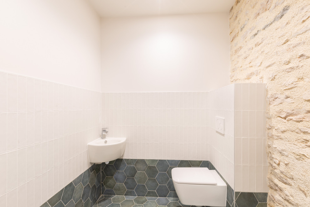 Foto på ett stort vintage flerfärgad toalett, med en vägghängd toalettstol, flerfärgad kakel, keramikplattor, flerfärgade väggar, klinkergolv i keramik, ett väggmonterat handfat, kaklad bänkskiva och blått golv