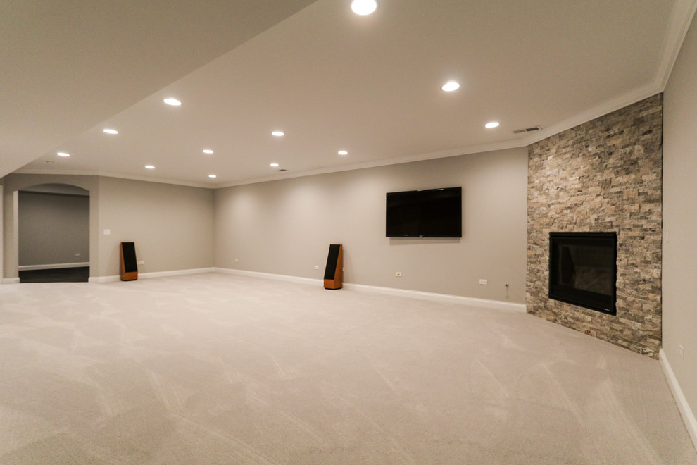 Expansive contemporary fully buried basement in Chicago with beige walls, carpet, a corner fireplace, a stone fireplace surround and grey floor.