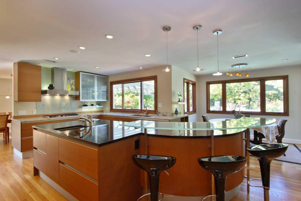 Photo of a large midcentury galley eat-in kitchen in San Diego with an undermount sink, flat-panel cabinets, medium wood cabinets, glass benchtops, green splashback, glass tile splashback, stainless steel appliances, medium hardwood floors, with island, turquoise floor, grey benchtop and coffered.