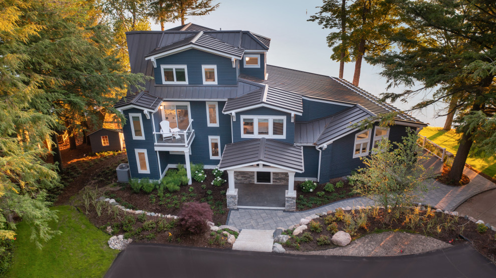 This is an example of a large traditional blue house exterior in Other with four or more storeys, vinyl siding, a metal roof and a grey roof.