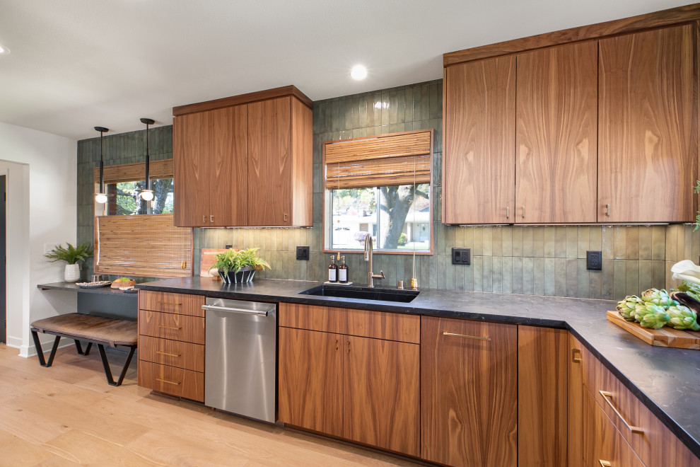 Example of a mid-sized 1950s galley light wood floor eat-in kitchen design in Portland with a drop-in sink, flat-panel cabinets, medium tone wood cabinets, granite countertops, green backsplash, porcelain backsplash, stainless steel appliances, no island and black countertops