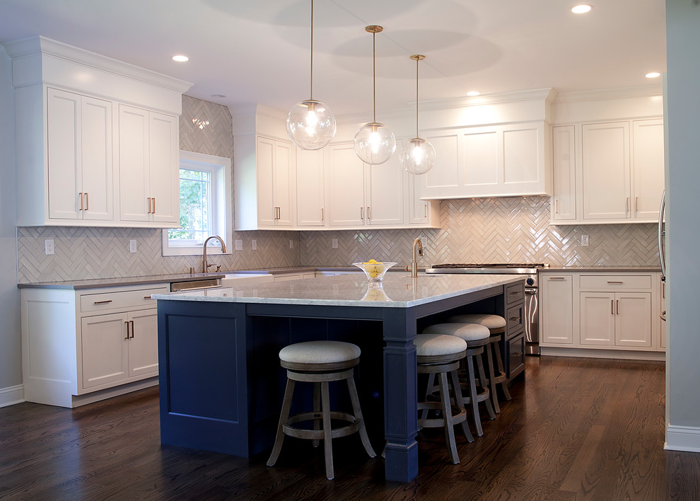 This is an example of a large traditional u-shaped open plan kitchen in Philadelphia with a farmhouse sink, shaker cabinets, white cabinets, marble benchtops, white splashback, porcelain splashback, stainless steel appliances, dark hardwood floors and with island.