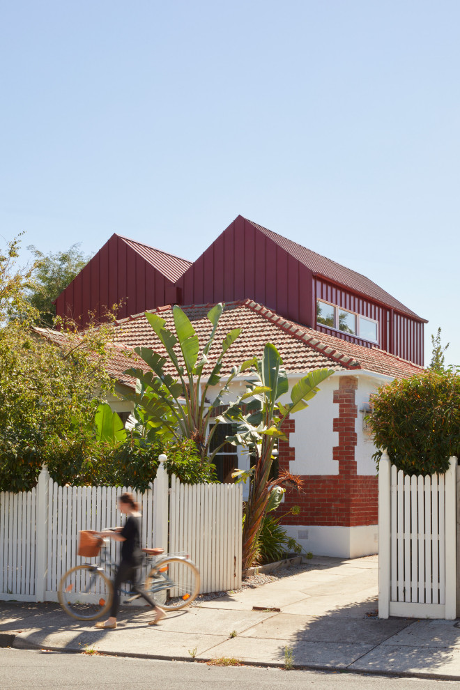 Photo of a mid-sized scandinavian two-storey red house exterior in Melbourne with metal siding.