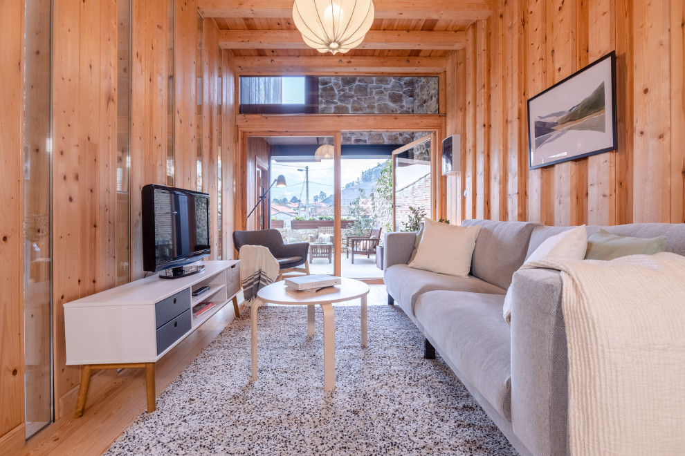 Идея дизайна: открытая гостиная комната в белых тонах с отделкой деревом в скандинавском стиле с светлым паркетным полом, отдельно стоящим телевизором, деревянным потолком и деревянными стенами