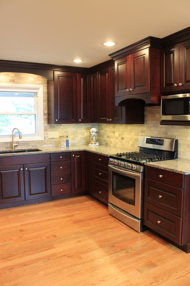 Eat-in kitchen - mid-sized transitional u-shaped laminate floor eat-in kitchen idea with an undermount sink, raised-panel cabinets, dark wood cabinets, quartz countertops, gray backsplash, porcelain backsplash, stainless steel appliances and no island
