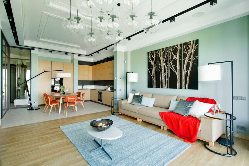 Contemporary open concept living room in Moscow with green walls and light hardwood floors.
