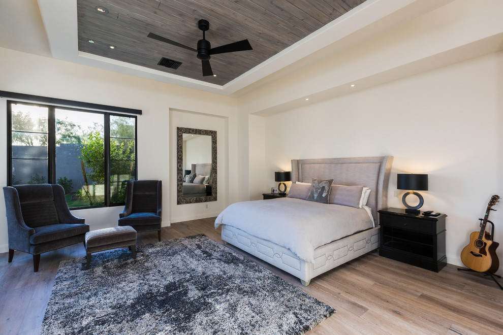 This is an example of a large contemporary master bedroom in Phoenix with beige walls, light hardwood floors, brown floor and a ribbon fireplace.