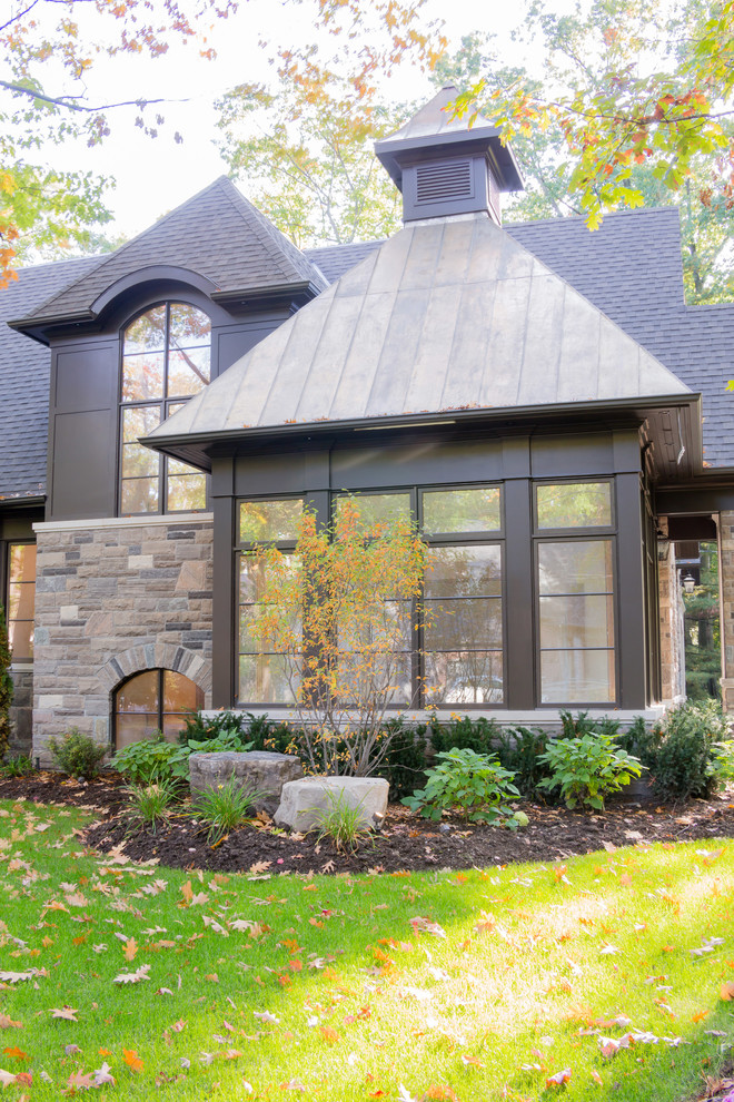 Photo of a large traditional two-storey exterior in Toronto with stone veneer.