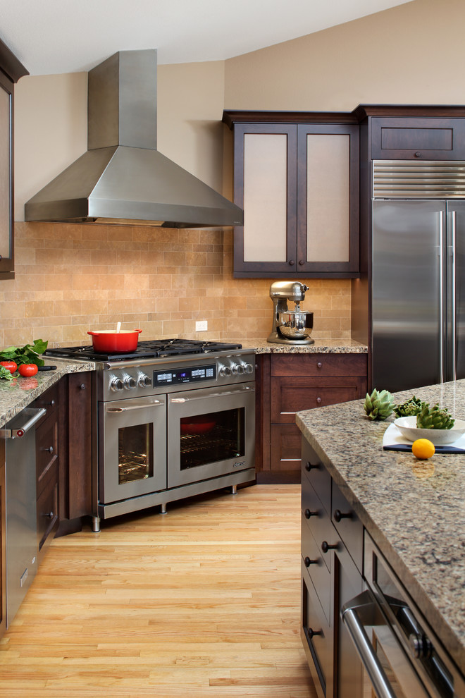 Example of a transitional light wood floor open concept kitchen design in San Francisco with dark wood cabinets, quartz countertops, beige backsplash, stone tile backsplash, stainless steel appliances, an island, an undermount sink and recessed-panel cabinets