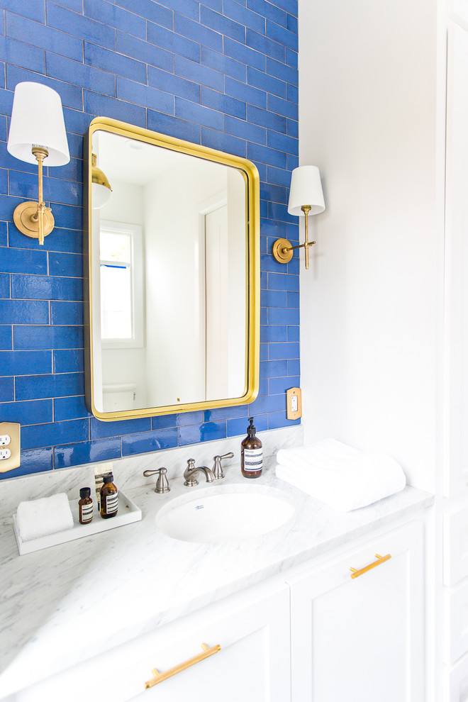 This is an example of a mid-sized modern 3/4 bathroom in Minneapolis with recessed-panel cabinets, white cabinets, an open shower, blue tile, ceramic tile, white walls, ceramic floors, a drop-in sink, marble benchtops, white floor and white benchtops.