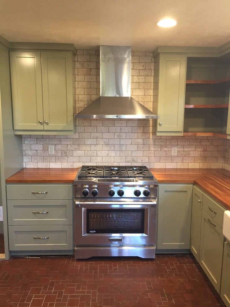 This is an example of a large country l-shaped eat-in kitchen in Austin with shaker cabinets, green cabinets, wood benchtops, beige splashback, stone tile splashback and stainless steel appliances.
