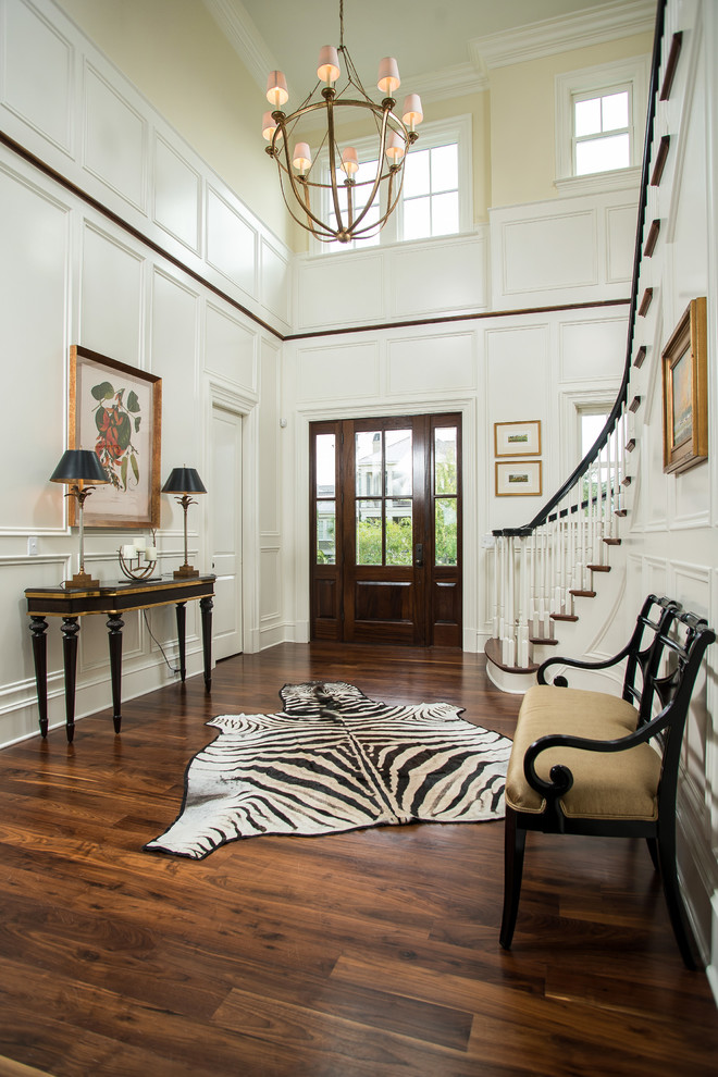 Photo of a large transitional foyer in Charleston with dark hardwood floors, a single front door, a dark wood front door, yellow walls and brown floor.
