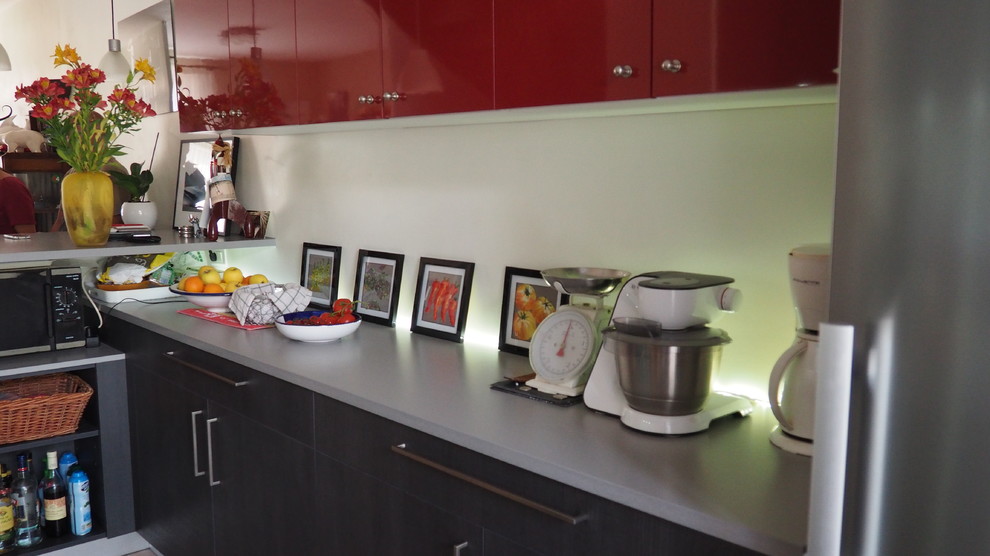 Large modern galley open plan kitchen in Nantes with a single-bowl sink, flat-panel cabinets, dark wood cabinets, laminate benchtops, red splashback, glass sheet splashback, stainless steel appliances, ceramic floors, with island and pink floor.