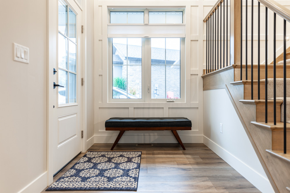 Inspiration for a small transitional laminate floor, brown floor and wall paneling foyer remodel in Toronto with white walls and a white front door