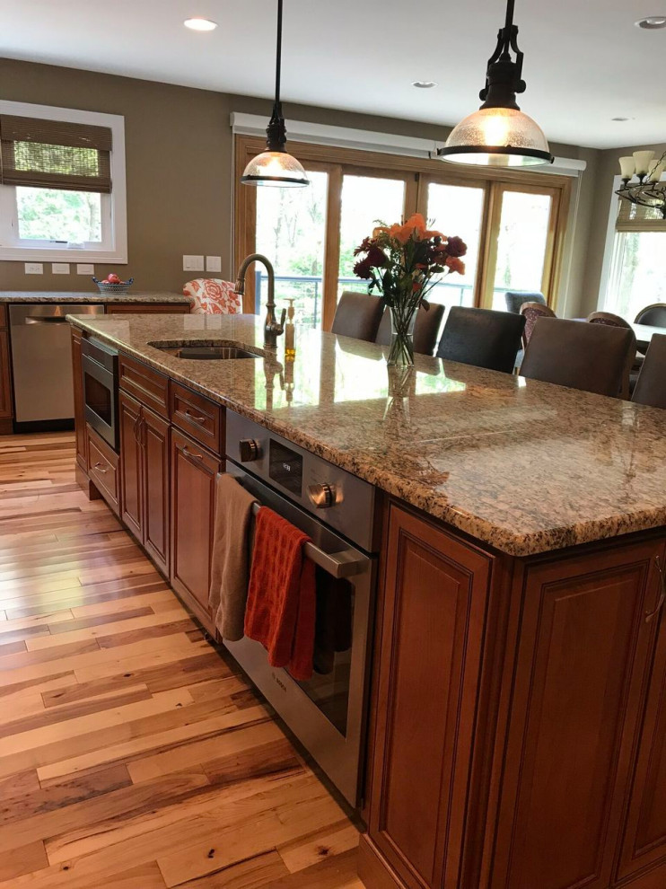Eat-in kitchen - large transitional l-shaped medium tone wood floor eat-in kitchen idea with a single-bowl sink, raised-panel cabinets, medium tone wood cabinets, granite countertops, stainless steel appliances and an island