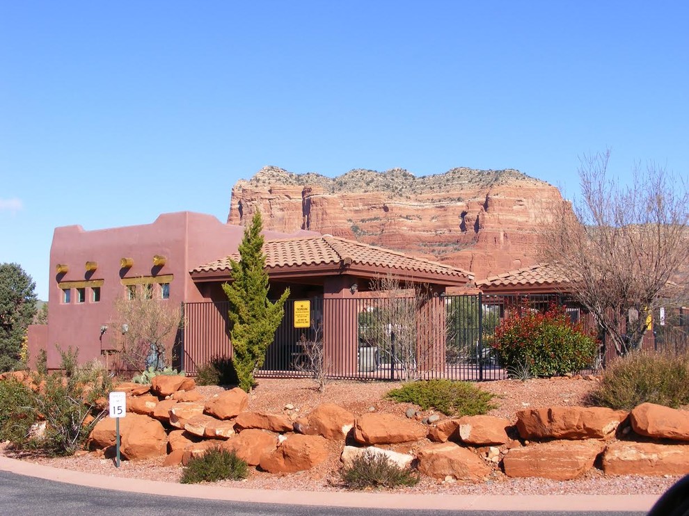 This is an example of a large one-storey stucco brown house exterior in Phoenix with a flat roof and a tile roof.