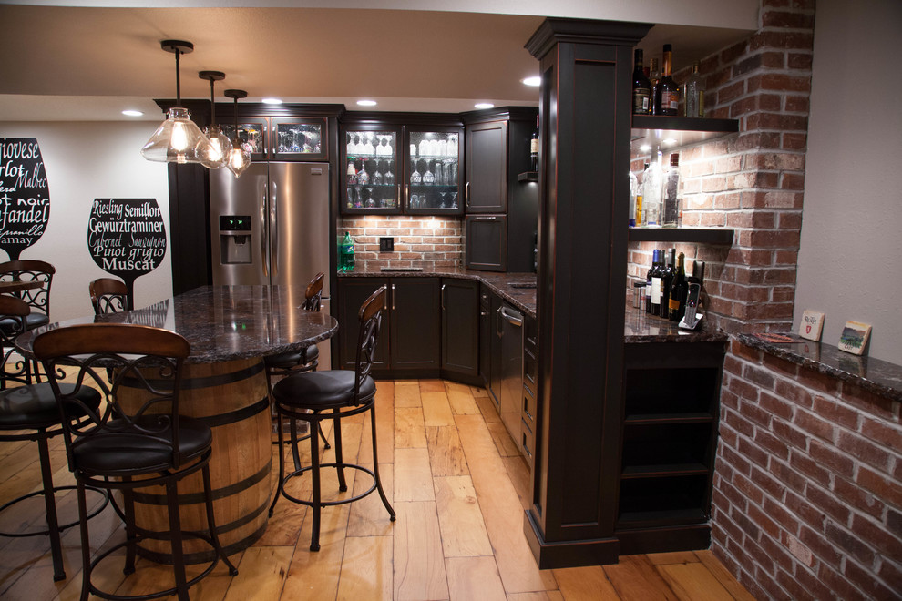 Inspiration for a large contemporary l-shaped seated home bar in St Louis with an undermount sink, recessed-panel cabinets, dark wood cabinets, granite benchtops, red splashback, brick splashback and medium hardwood floors.