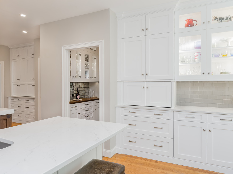 Inspiration for a transitional u-shaped eat-in kitchen remodel in Providence with an undermount sink, white cabinets, quartzite countertops, glass tile backsplash, stainless steel appliances and an island
