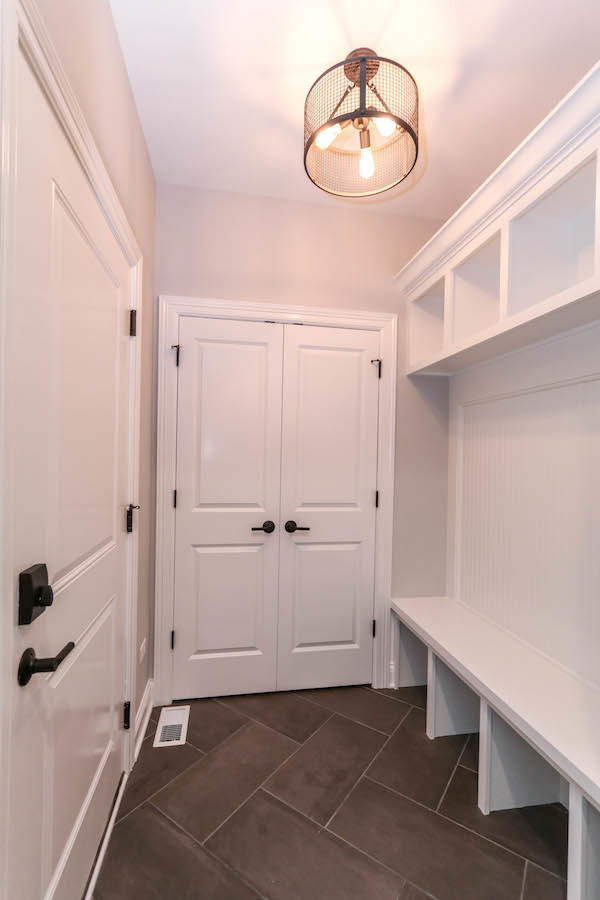 This is an example of a mid-sized arts and crafts dedicated laundry room in Chicago with an undermount sink, shaker cabinets, white cabinets, quartz benchtops, white walls, ceramic floors, a side-by-side washer and dryer, black floor and white benchtop.