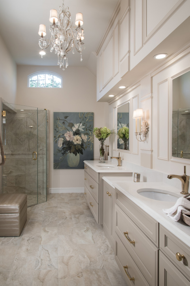 This is an example of a mid-sized traditional master bathroom in St Louis with raised-panel cabinets, white cabinets, a corner tub, an open shower, a one-piece toilet, white tile, stone slab, beige walls, marble floors, a drop-in sink, solid surface benchtops and a hinged shower door.