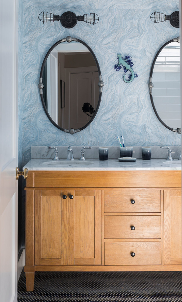 Photo of a beach style bathroom in New York with medium wood cabinets, blue walls, mosaic tile floors, an undermount sink, black floor, white benchtops and shaker cabinets.