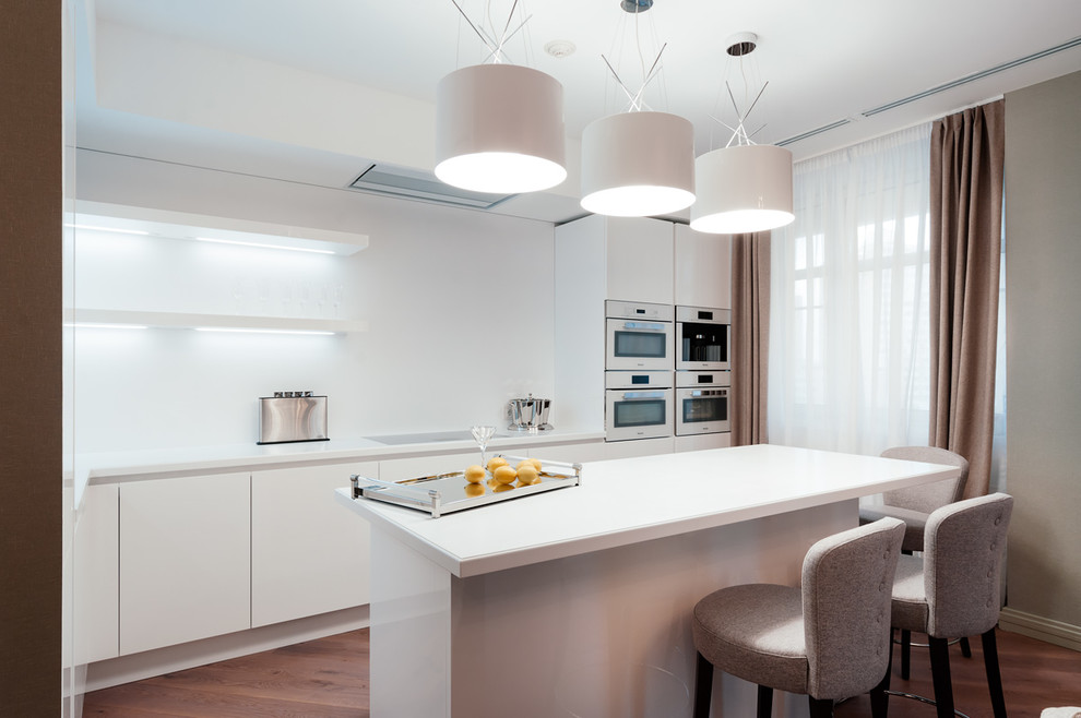 Design ideas for a contemporary single-wall eat-in kitchen in Moscow with flat-panel cabinets, white cabinets, white splashback, medium hardwood floors, with island and stainless steel appliances.