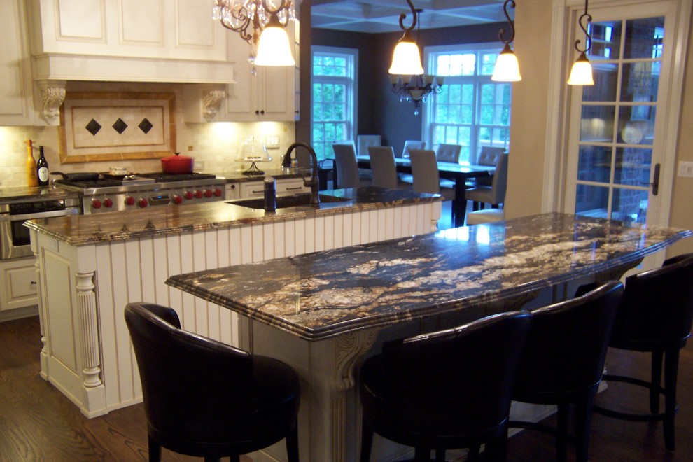 This is an example of a traditional l-shaped eat-in kitchen in Chicago with an undermount sink, raised-panel cabinets, white cabinets, granite benchtops, multi-coloured splashback, ceramic splashback and stainless steel appliances.
