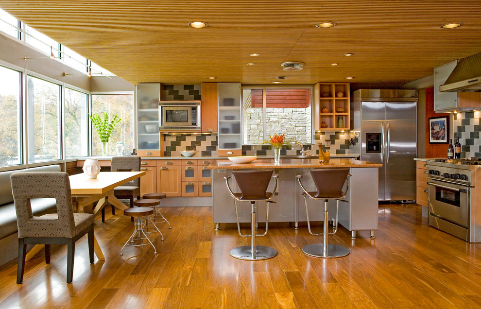 This is an example of a contemporary eat-in kitchen in Nashville with medium wood cabinets, multi-coloured splashback, stainless steel appliances, medium hardwood floors and with island.