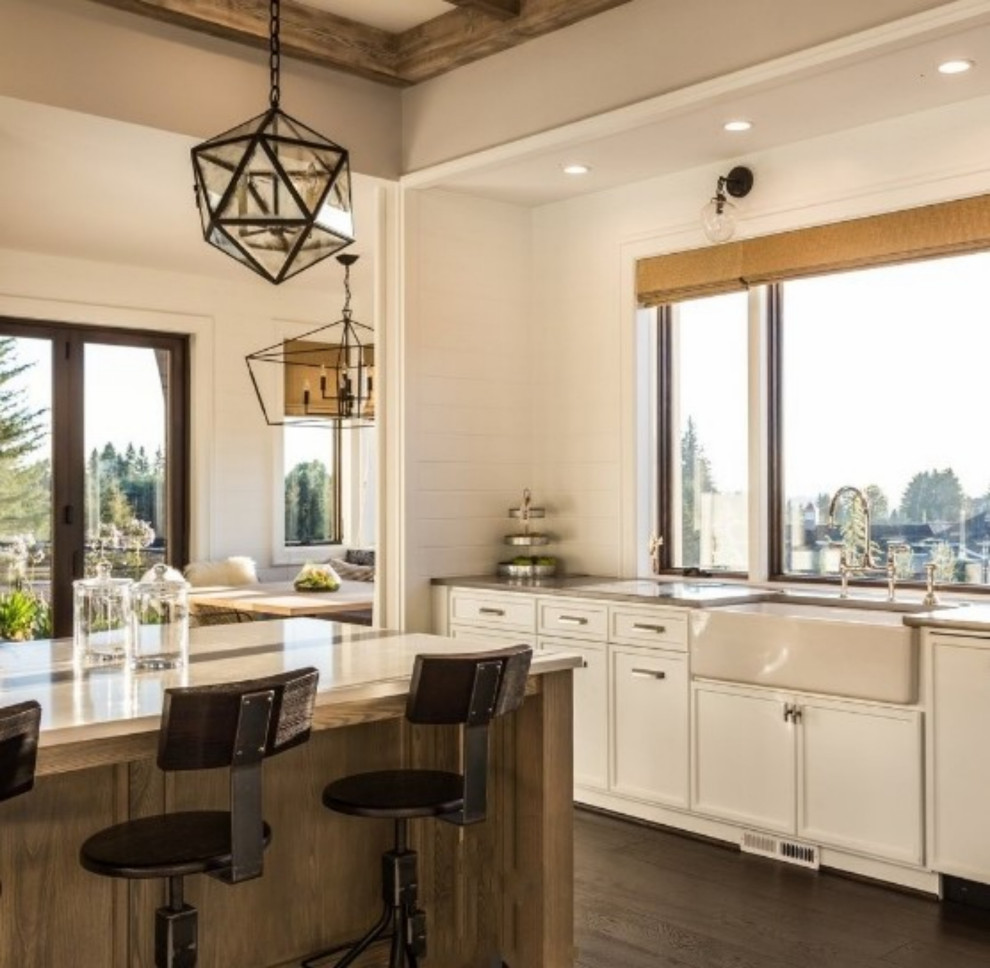 This is an example of a contemporary eat-in kitchen in San Francisco with a farmhouse sink, shaker cabinets, white cabinets, quartz benchtops, white appliances, dark hardwood floors, with island and exposed beam.