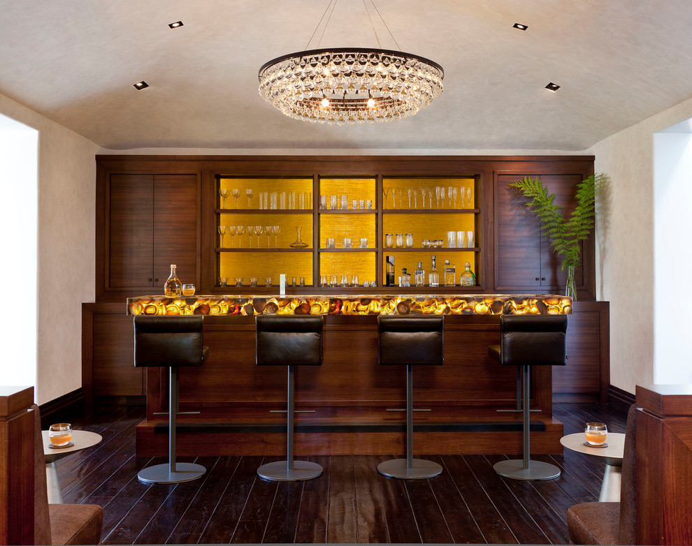 This is an example of a mediterranean galley seated home bar in Los Angeles with dark wood cabinets, yellow splashback, dark hardwood floors, yellow benchtop and flat-panel cabinets.
