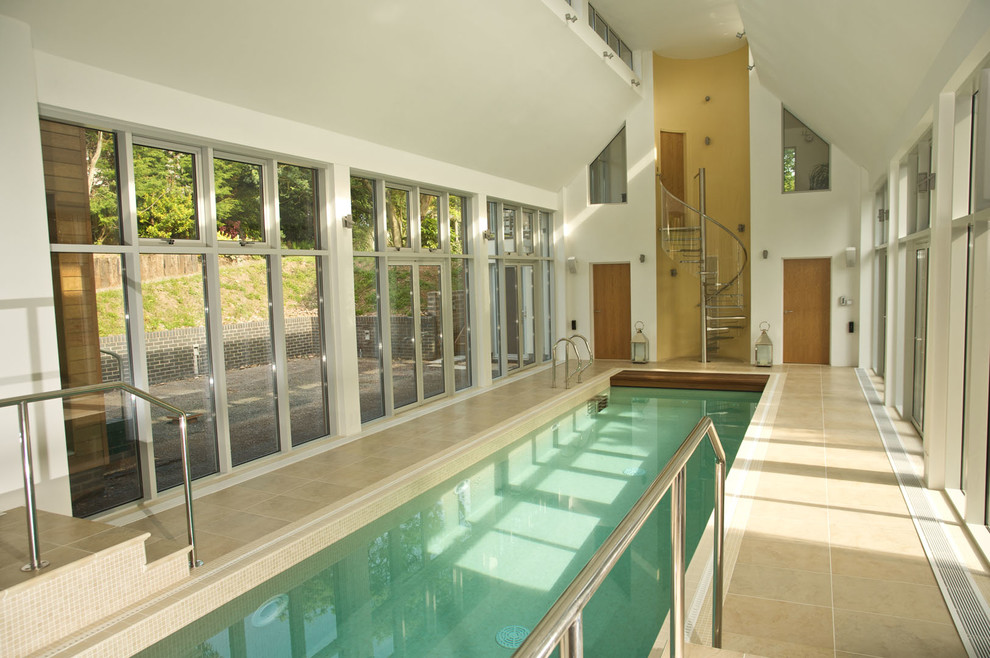 Photo of a contemporary indoor rectangular pool in Devon with a pool house and tile.