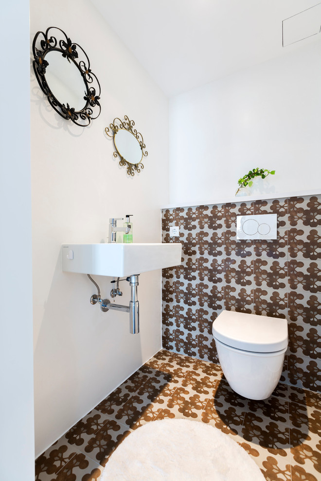 Inspiration for a small transitional powder room in Palma de Mallorca with a wall-mount toilet, white walls, ceramic floors and a wall-mount sink.