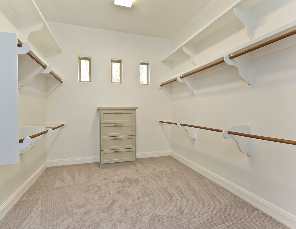 This is an example of a mid-sized transitional gender-neutral dressing room in Austin with shaker cabinets, beige cabinets and carpet.
