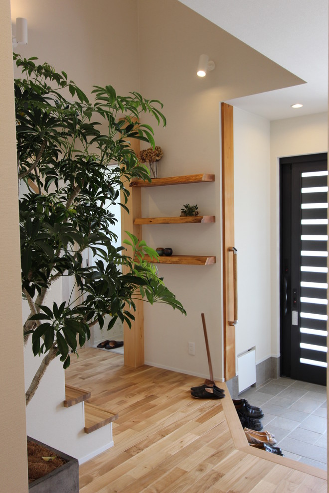 This is an example of a contemporary entryway in Nagoya with white walls, a single front door, a black front door and grey floor.