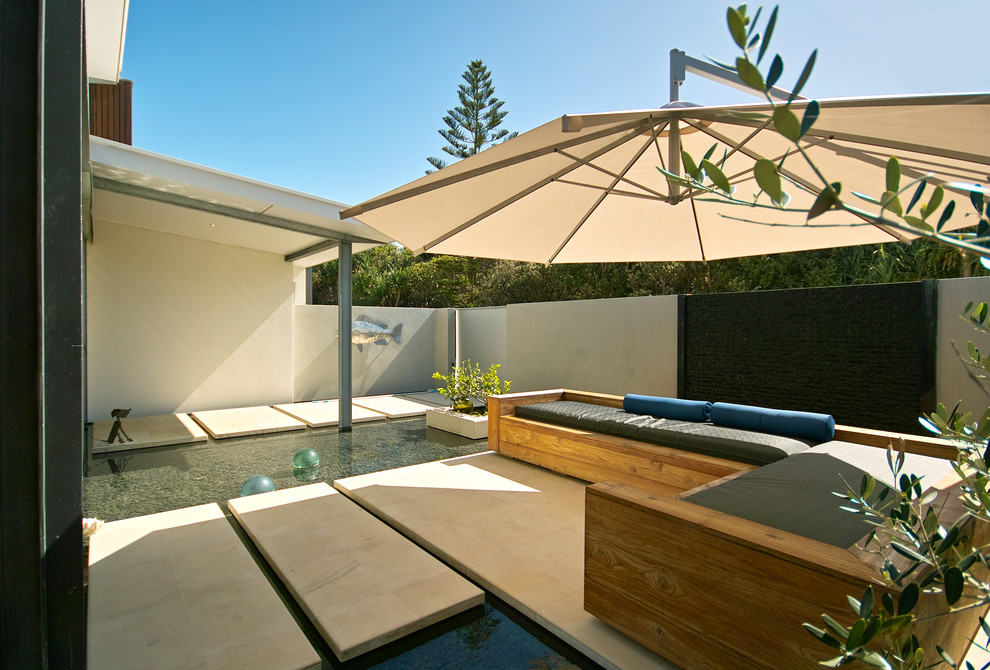 This is an example of a beach style patio in Brisbane with a water feature.