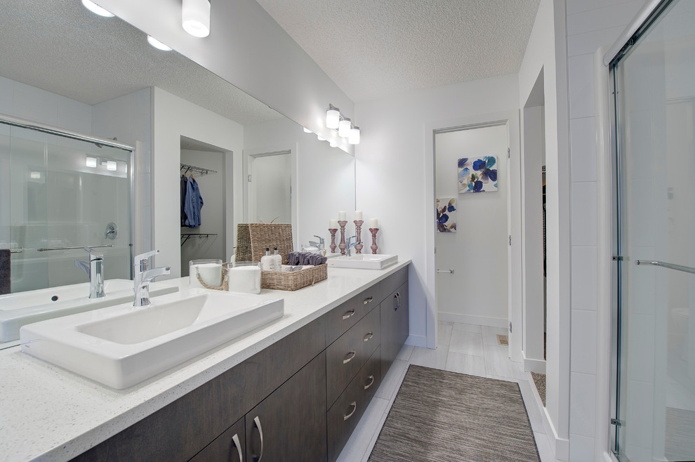 Photo of a mid-sized transitional master bathroom in Edmonton with flat-panel cabinets, brown cabinets, an alcove shower, a two-piece toilet, white tile, ceramic tile, white walls, vinyl floors, a drop-in sink, laminate benchtops, white floor, a sliding shower screen and white benchtops.