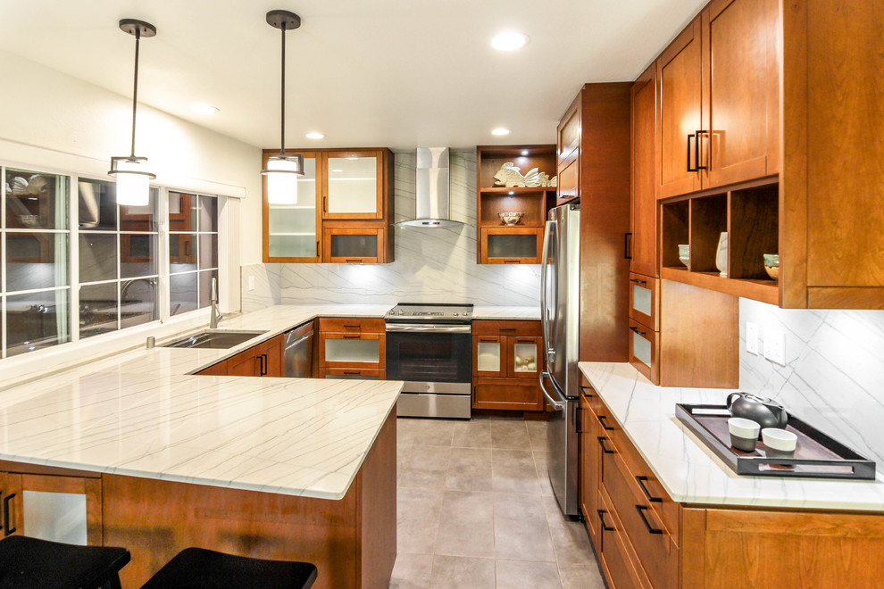This is an example of a mid-sized modern u-shaped eat-in kitchen in San Diego with a single-bowl sink, recessed-panel cabinets, medium wood cabinets, quartzite benchtops, white splashback, stone slab splashback, stainless steel appliances, cement tiles, a peninsula, grey floor and white benchtop.