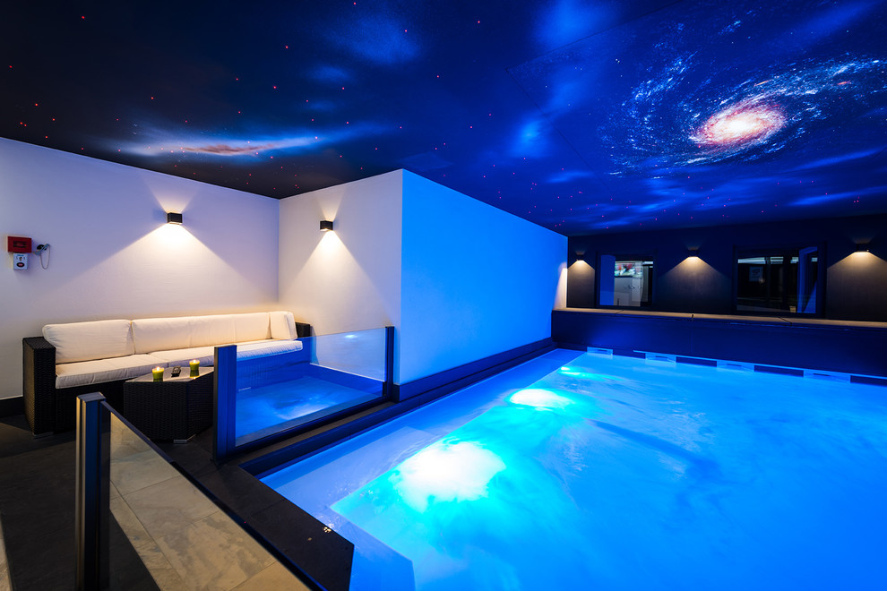 This is an example of a large contemporary indoor rectangular pool in Cologne with tile.