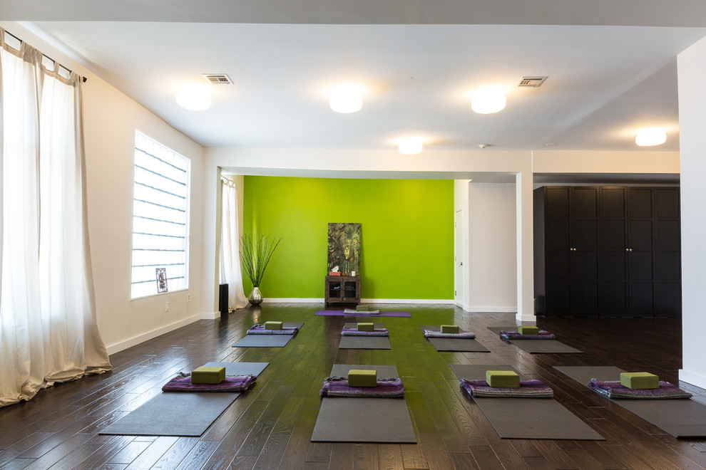Large contemporary home yoga studio in New York with dark hardwood floors and green walls.