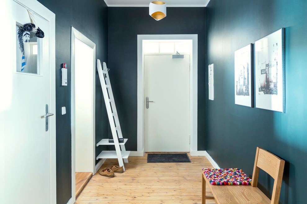 Photo of a large contemporary hallway in Berlin with blue walls and medium hardwood floors.