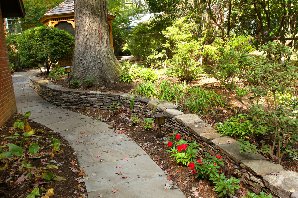Photo of a mid-sized traditional backyard partial sun garden in DC Metro with a retaining wall and mulch.