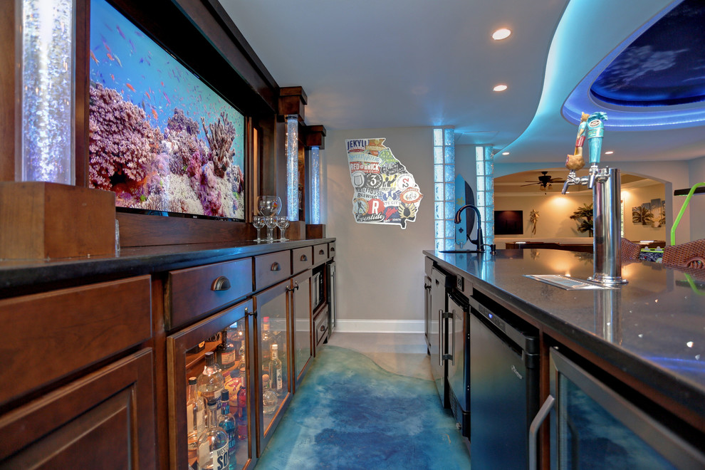 This is an example of a mid-sized beach style galley seated home bar in Atlanta with concrete floors, an undermount sink, glass-front cabinets, dark wood cabinets, granite benchtops and blue floor.