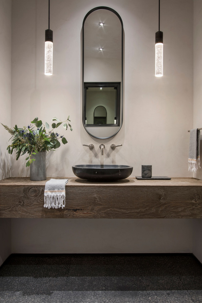 Ispirazione per un bagno di servizio stile rurale con pavimento con piastrelle a mosaico, lavabo a bacinella, top in legno e mobile bagno sospeso