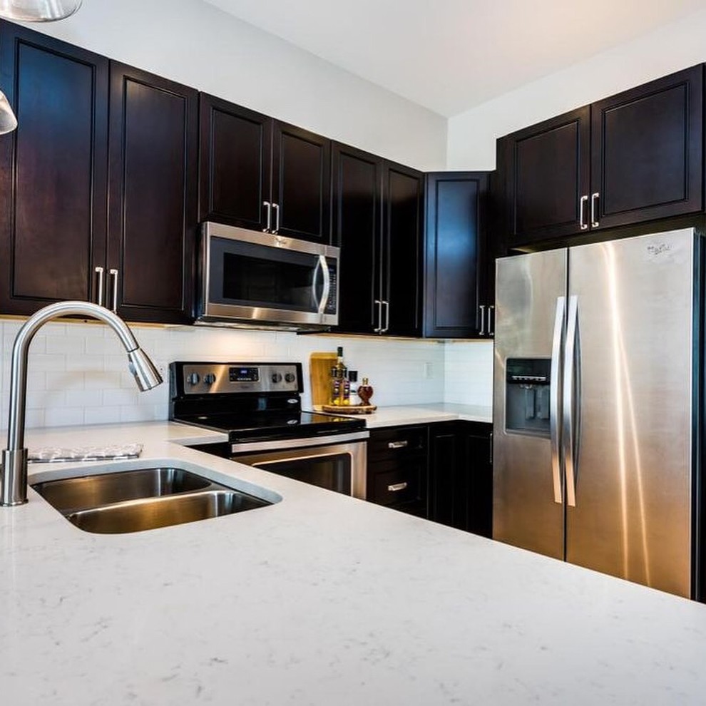 Eat-in kitchen - mid-sized transitional u-shaped eat-in kitchen idea with a double-bowl sink, shaker cabinets, dark wood cabinets, quartz countertops, white backsplash, subway tile backsplash, stainless steel appliances, no island and white countertops