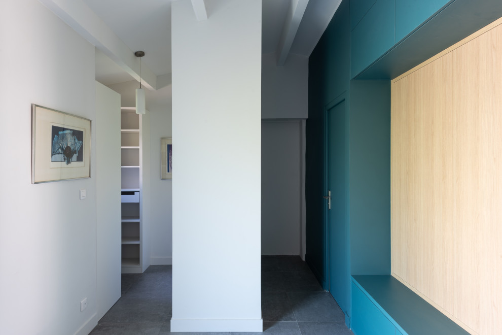 Immagine di un grande ingresso scandinavo con pareti blu, pavimento con piastrelle in ceramica, una porta a due ante, una porta grigia, pavimento grigio e travi a vista
