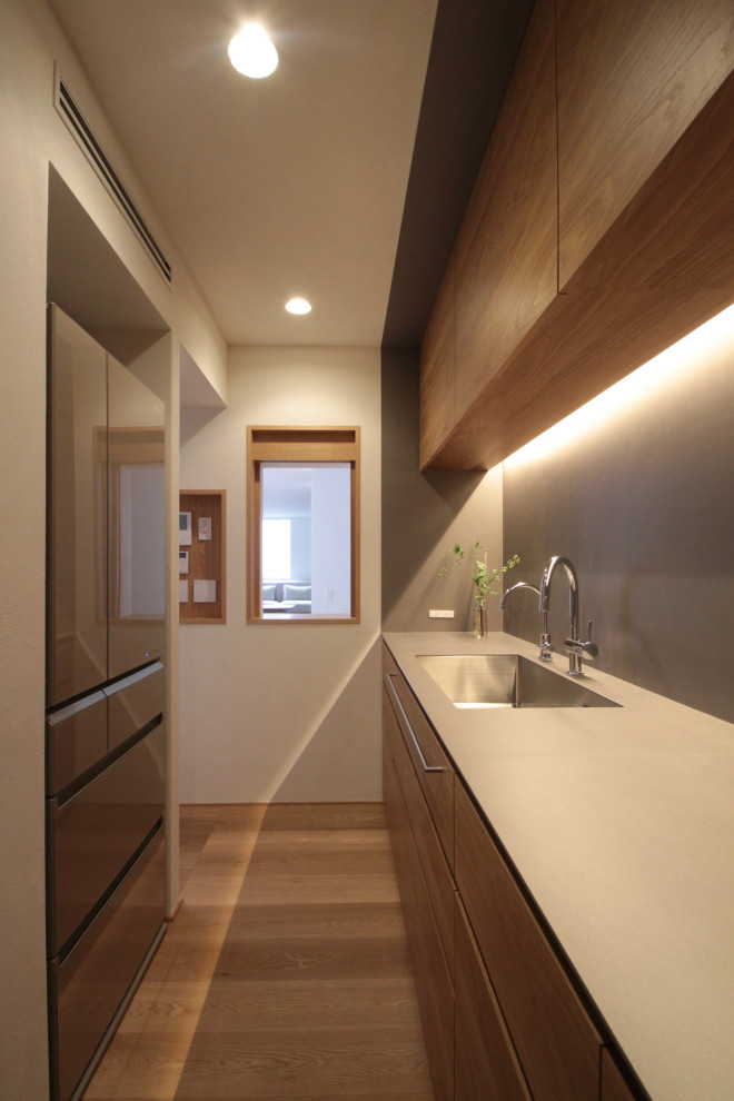 Mid-sized contemporary galley separate kitchen in Tokyo with an undermount sink, flat-panel cabinets, medium wood cabinets, grey splashback, stainless steel appliances, no island, beige floor and beige benchtop.