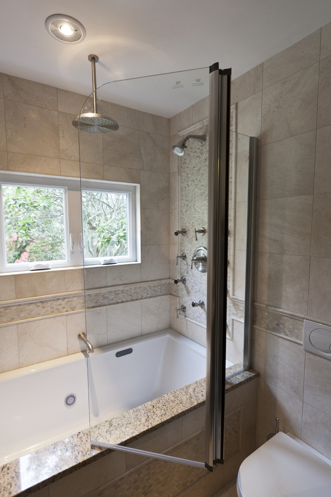 Small traditional bathroom in Bridgeport with an undermount sink, shaker cabinets, dark wood cabinets, granite benchtops, an undermount tub, a shower/bathtub combo, a wall-mount toilet, beige tile, stone tile, beige walls and marble floors.