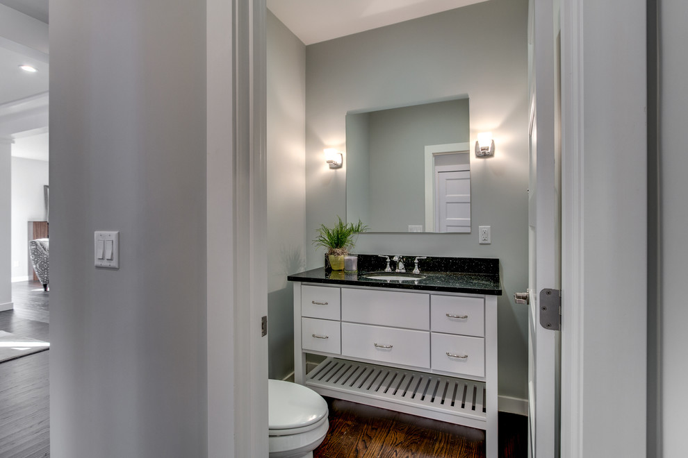 Mid-sized contemporary powder room in Boston with flat-panel cabinets, white cabinets, a two-piece toilet, grey walls, medium hardwood floors, an undermount sink, marble benchtops and brown floor.